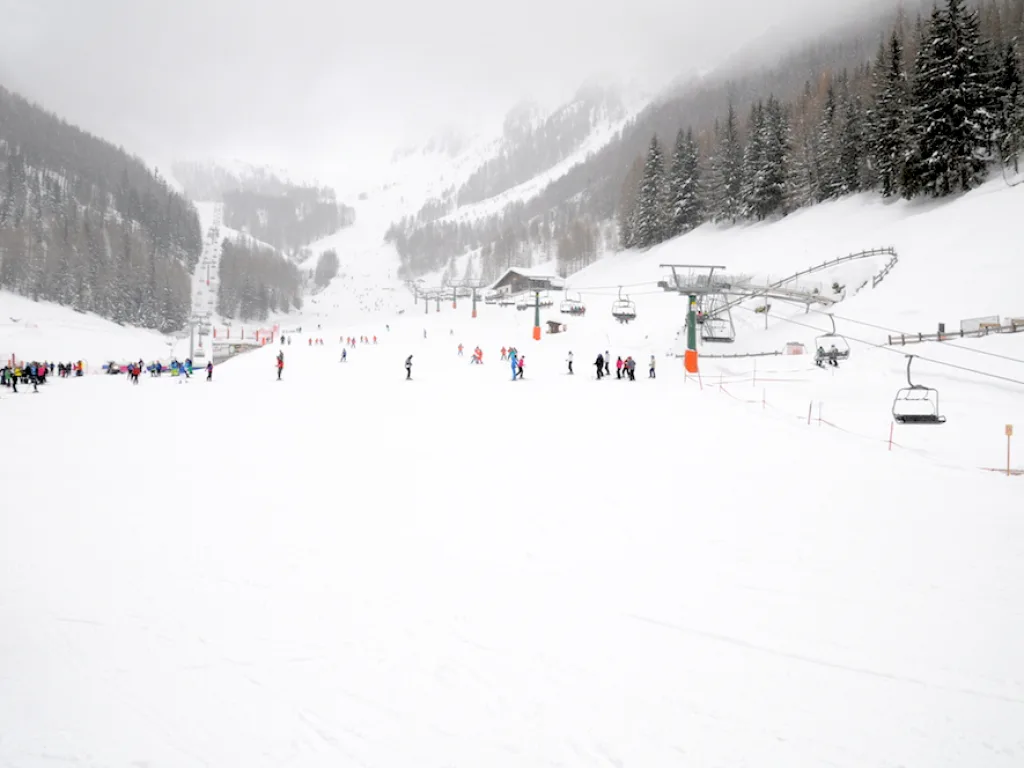 Weite Piste im Nebel mit einzelnen Fahrenden.